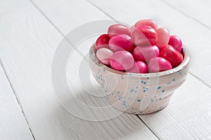 Colorful gum in a bowl on a white wooden background