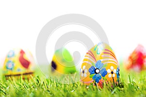 Colorful hand painted Easter eggs in grass. Spring theme, white copy-space