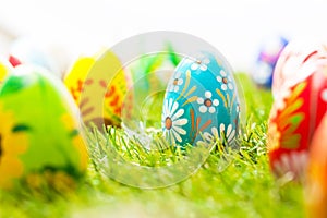 Colorful hand painted Easter eggs in grass. Spring theme, white copy-space