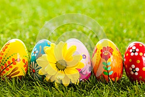 Colorful hand painted Easter eggs and spring flowers in grass