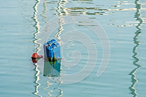 Colorful handmade buoy in deep blue sea waters on sunset. Pilotage marking maritime channel.