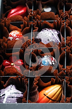Colorful handmade chocolates in a box on a dark background