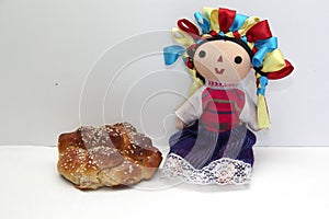 Colorful handmade cloth doll with pan de muerto from the town with sesame in the offering for the Day of the All Souls and All Sai