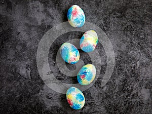 Colorful handmade Easter eggs painted like Earth in row on black marble background with copy space for Easter text