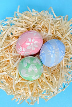 Colorful handmade painted Easter eggs in the nest on a blue background. Easter eggs decorated by a child