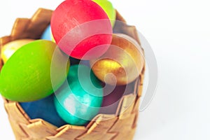Colorful handmade painted Easter eggs in wicker basket on white background