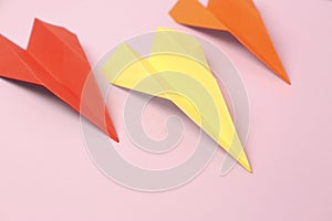 Colorful handmade paper planes on pink background, closeup