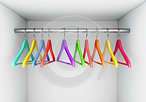 Colorful hangers on cloth rail in wardrobe