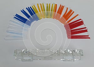 Colorful Hannukah candles creating the shape of a rainbow with a glass chanukkah lamp