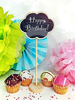 Colorful happy birthday cupcakes with candles with compliments. Birthday cupcake and black board with chalk inscription