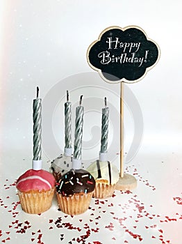 Colorful happy birthday cupcakes with candles with compliments. Birthday cupcake and black board with chalk inscription