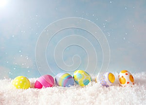 Colorful Happy Easter Eggs in Snow against Blue Sky with sunlight with room or space for copy, text, or your words. Horizontal