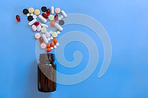 Colorful heap of pills bottle with medicine on blue background.