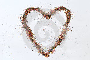 Colorful heart made from shavings of pencils on white background. Ideas with color pencil dust. Copy space