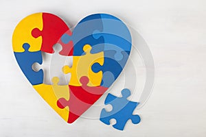 A colorful heart made of symbolic autism puzzle pieces.