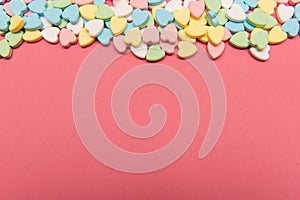 Colorful heart shaped candy on top of pink surface , valentine`s day love concept