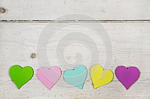 Colorful hearts on old wooden white shabby chic background.