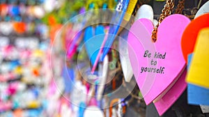 Colorful hearts on the street hanging on wall with text message - Be kind to yourself. Self love and care concept.