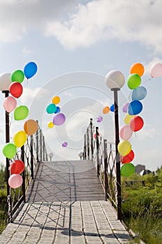 Colorful helium baloons at bridge opposite blue sky