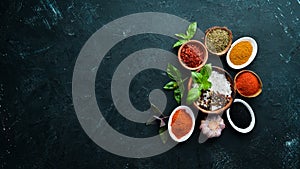 Colorful herbs and spices for cooking. Indian spices. On a black stone background.