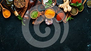 Colorful herbs and spices for cooking. Indian spices. On a black stone background.