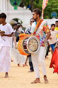 Colorful Hindu drummer close-up, bare-footed drummers, and devotees gather in Ruhunu Maha