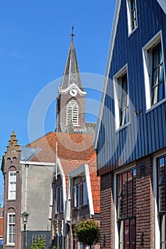 Colorful and historic house facades in De Rijp, Alkmaar, North Holland, Netherlands, with the clock tower of St Bonifatius church