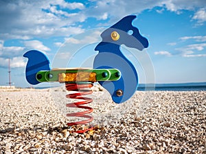 Colorful horse spring rider on the rocky beach under blue cloudy sky