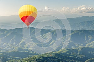 Colorful hot air balloon above forest mountain