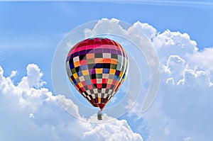 Colorful hot air balloon flying in the blue sky with white clouds.