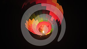 Colorful hot air balloon flying with flames against dark sky at night