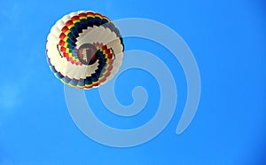 A colorful hot air balloon flying in the large blue sky.