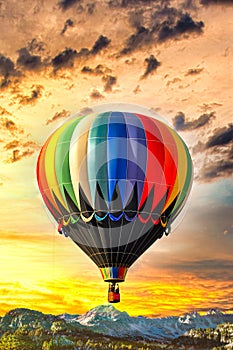 Colorful hot air balloon flying over the mountains against a vivid sky and landscape