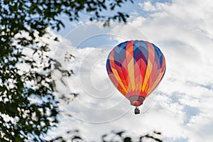 Colorful hot air balloon framed by leaves