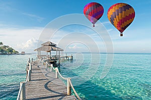 Colorful hot air balloon over Phuket beach with blue sky background, Phuket, Thailand Tropical hut and wooden bridge at holiday r