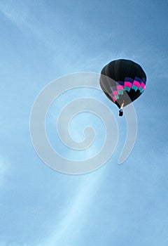 A colorful hot air balloon rises into an azure sky