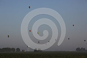 Colorful hot air balloons fly in mass above the Iowa countryside.