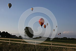 Colorful hot air balloons fly in mass above the Iowa countryside.