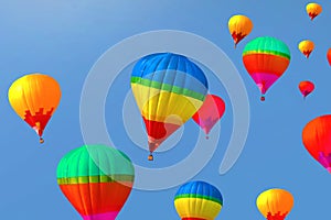 Colorful hot air balloons flying away in blue summer sky