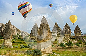 Colorful hot air balloons flying over volcanic cliffs at Cappadocia