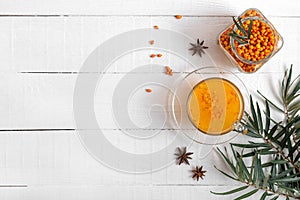 Colorful hot natural sea buckthorn tea in a glass cup, fresh raw berries and leaves, honey, anise and cinnamon sticks. Vitaminic