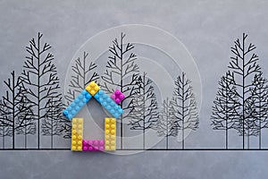 Colorful house model with drawing of tree on grey background