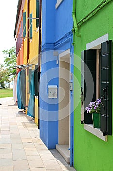 Colorful houses in Burano, houses painted in bright colors, small colorful houses, flowers in the windows, fabric curtain on the f