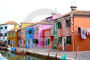 Colorful houses in Burano island. Canal view with boats.