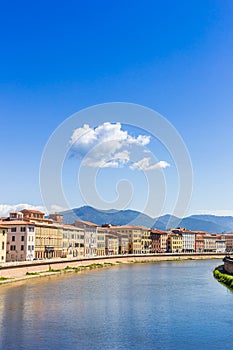 Colorful houses with mountain backdrop at the Arno river in Pisa