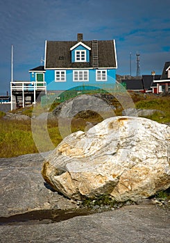 Colorful houses of Nuuk, rock covered by green grass in the foreground at sunny day
