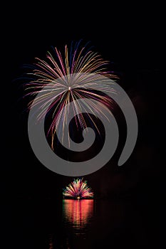 Colorful huge mine and fountain in fireworks over Brno`s Dam with lake reflection