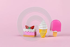 Colorful ice cream and cake figurines on a pink background