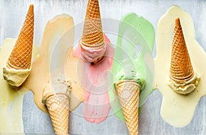 Colorful ice cream cones of different flavors. Melting scoops. Top view, steel metal background.