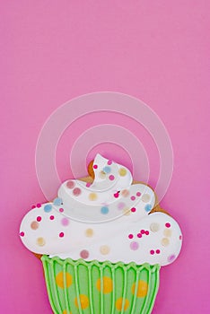 Colorful icing cookie in cupcake shape on pink background